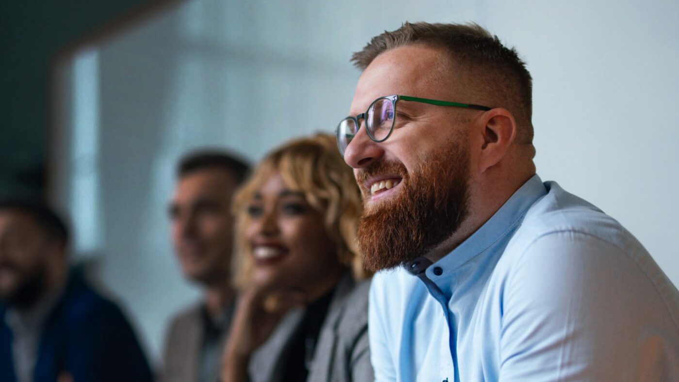 A professional listening intently during a Mental Wealth Revolution session, with colleagues alongside